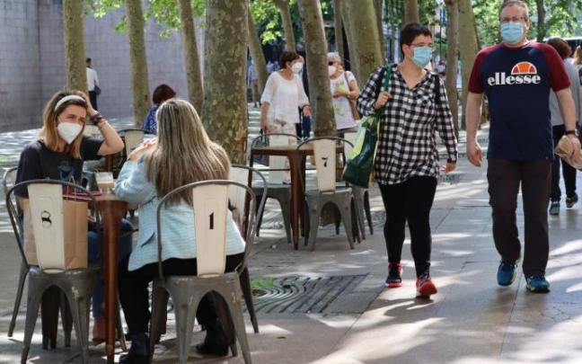 Personas sentadas en la terraza de un bar con mascarilla para evitar contagios de coronavirus