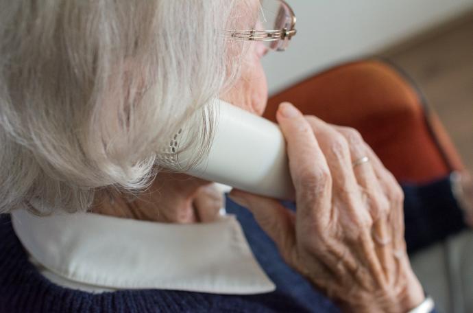 Una anciana habla por un teléfono clásico.