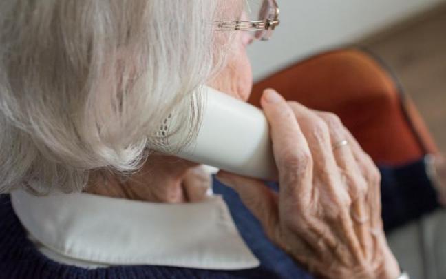 Una anciana habla por un teléfono clásico. Una anciana habla por un teléfono clásico.