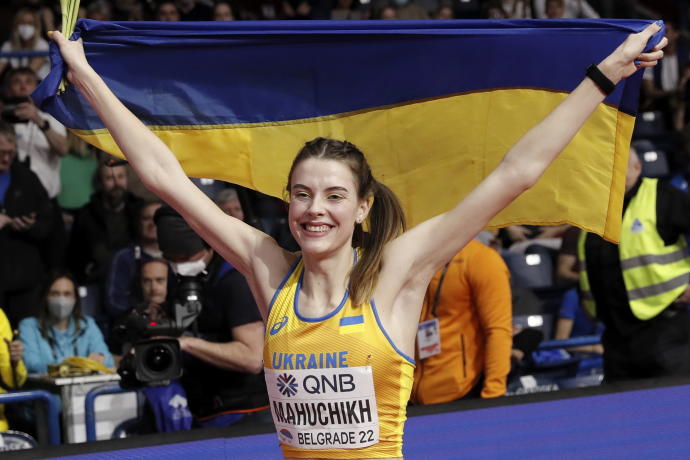 Yaroslava Mahuchikh posa sonriente con la bandera de Ucrania.