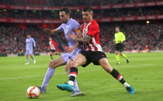 Yuri Berchiche disputa un balón por la banda a Busquets.