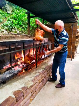 Javier Juanena, el gestor de la cueva restaurante, gira el cordero que se está haciendo a la brasa para que no se queme