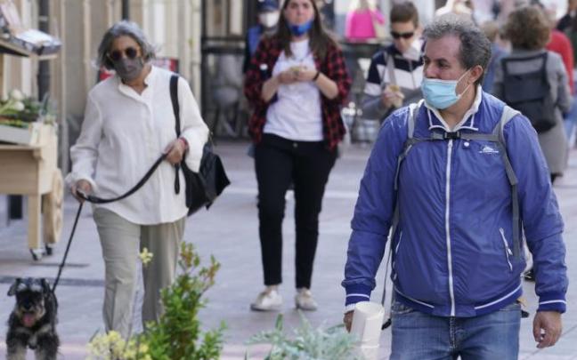 Personas andando por la calle con mascarilla.
